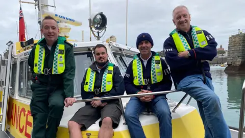 Four men sat on the bow of the Flying Christine.