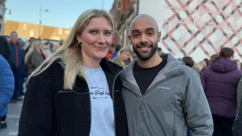Danny Fullbrook/BBC A couple smile together on an outdoor town centre street