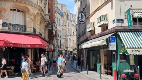 James Fitzgerald / BBC People walk through a street in Paris' Latin Quarter