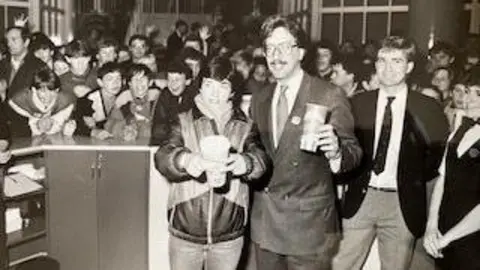 Charles J. Wesoky A black and white photo shows the inside of The Point. There are huge crowds and a girl is holding a cup full of popcorn next to a man in a smart suit
