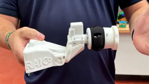 Sellafield A white plastic attachment which is attached to a robot to swab surfaces. It is being held out by a man.