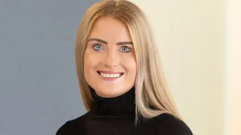 SQUIRE PATTON BOGGS Simone White, who has long straight blonde hair and wears a black polo neck jumper, smiles at the camera in a work headshot