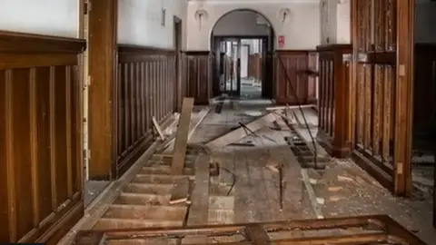 Barbie Lindsay Inside a hallway within County Hall. Floor boards have been torn up with panels of wood lying scattered around.