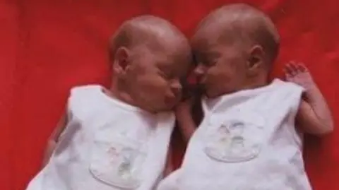 Supplied Newborn identical twins lying together asleep. 