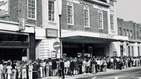 The Regent A black and white image taken outside a theatre showing long queues of people outside. The name above the canopy is Gaumont. 