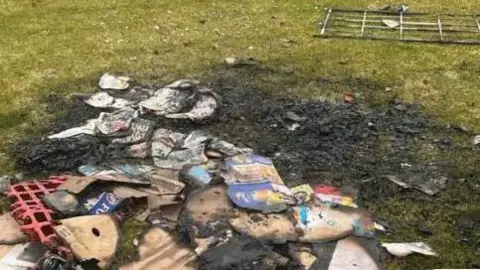 Local Democracy Reporting Service The aftermath of a fire on the grounds of a football pitch - the grass is blackened and there is rubbish strewn across there 