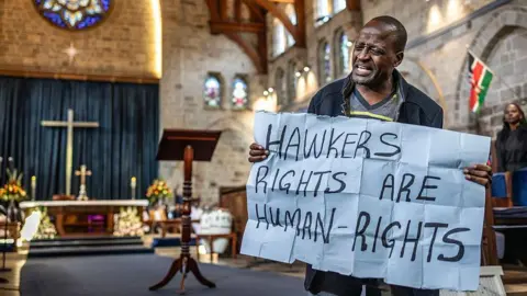 AFP via Getty Image A protester holds a placard written 'Hawkers rights are human-rights'