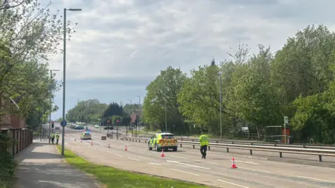 BBC Scene of police and dual carriageway and one car stopped in the road and one crashed into railings