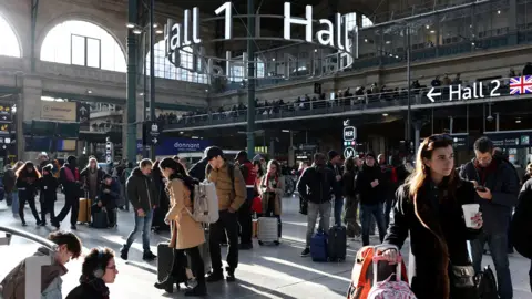 Passengers wait inside the departure hall as traffic at the Gare du Nord train station