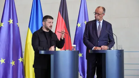 German counselor Friedrich Mirz and Ukrainian President Voludmir Zelinski stand next to each other on the podium while attending a joint press conference in the counselor after a virtual meeting hosted by Mirz between European leaders and US President Donald Trump