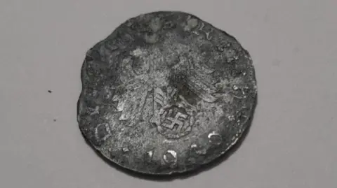 Paul Stockreiter Heavily damaged and worn German coin. The Reichsadler - an heraldic eagle - on top of a swastika can be seen on the Reichsmark and the date 1940 can be seen on the lower edge of the coin as well as letters from Deutsches Reich around the rest of the edge.