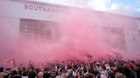 PA Media Fans gather with red flares outside St Mary's Stadium