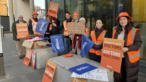 People wearing hi vis jackets and holding b anners on a picket line in Brighton
