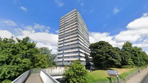 Nauls Mill House, a tall tower block surrounded by green trees and a grassy area