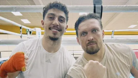 Lewis Williams with World heavyweight Champion Oleksandr Usyk. Williams is on the left, with orange tape on his right fist. Usyk is on the left.