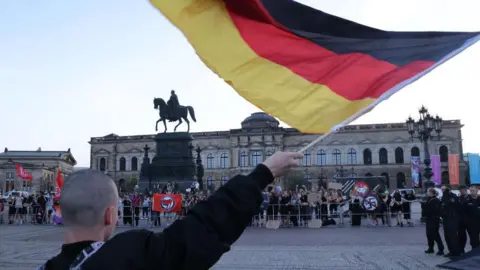 Getty Images Seorang pria memegang bendera Jerman saat berunjuk rasa di Dresden