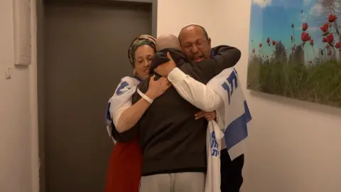 A freed hostage embraces two relatives after being released from Gaza.