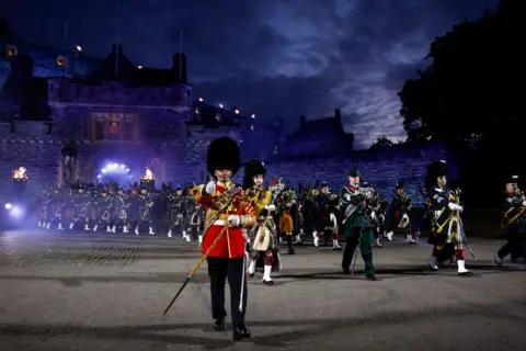 Getty Images A military band marches and plays in front of Edinburgh Castle at night during the Military Tattoo