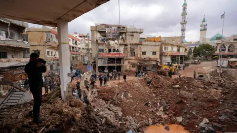 People inspect the damage where Israel's military carried out an airborne operation that dropped troops overnight, in the town of Nabi Chit. 