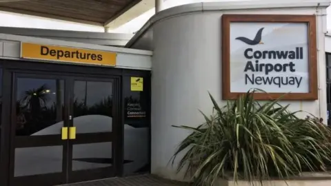 BBC entrance door to the departures area at Newquay Airport. Above a double set of doors is a yellow sign with black letters saying 