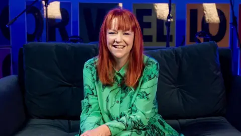 Bethan Elfyn, who has long red hair and is wearing a green top