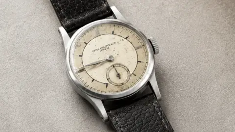 A picture of a rare Patek Philippe wristwatch. It has a leather strap and a glass face. 