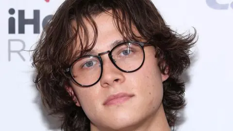 Getty Images Up close photo of David Kushner wearing glasses and staring into the camera lens with his chin slightly pointing down to the right 