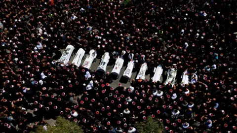 Reuters Mourners surround coffins in the streets