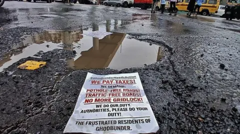 Getty Images A leaflet left behind by protesters in front of a massive pothole in Thane city where angry citizens had held a rally about traffic congestion and the poor state of road infrastructure. 