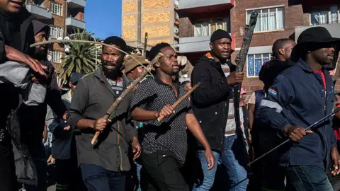 Getty Images South Africans holding sticks to protest illegal migration to their country