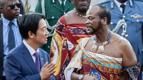 Taiwan's President Lai Ching-te (in navy blue suit white shirt and blue tie) and Eswatini's King Mswati III (in traditional royal regalia) talking