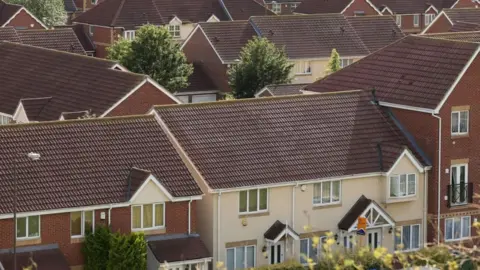 PA Media An aerial view of a residential area, with two-storey, red-brick and rendered houses. 