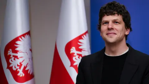 Jesse Eisenberg in front of a Polish flag