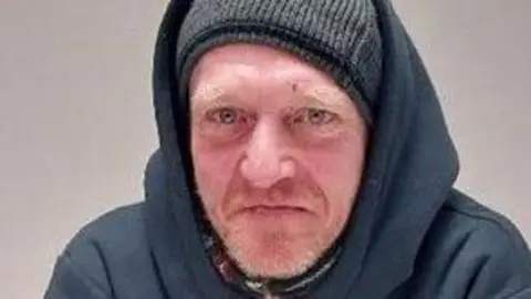 Matthew Weller wears a grey beanie hat under a dark hooded top.