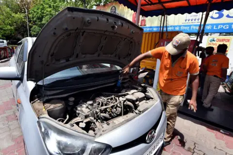 Hindustan Times via Getty Images An employee Handle CNG Gas dispenser for refuel CNG Vehicle fueling facility at CNG pump station Gole Market on April 14, 2022 in New Delhi, India. 
