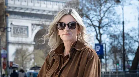 Lisa Bankworth, wearing shades and a brown jacket, poses for a photograph in Paris on 18 March 2026
