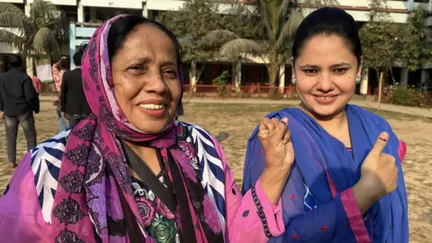Aakriti Thapar/BBC A mother and daughter smile on voting day. The daughter gives a thumbs up sign