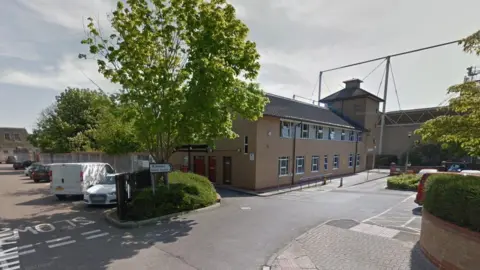 An image of the outside of the health centre with a view of its car park