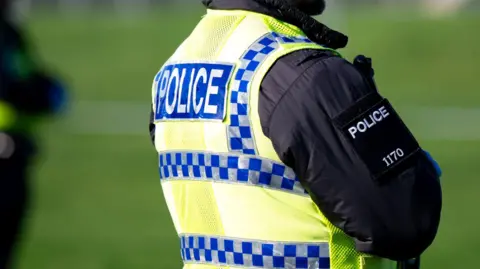 A police officer in uniform with his back turned to the camera