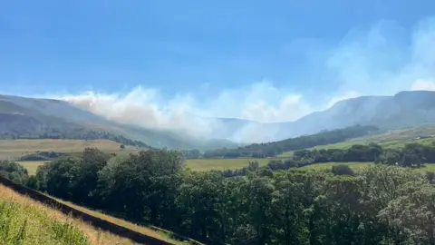 Smoke between hills on summer day
