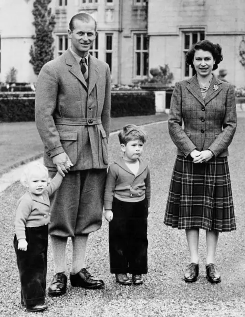 Topical Press Agency / Hulton Archive via Getty Images The young Queen wearing a different checked tweed blazer and darker tartan knee-length skirt, with the Duke of Edinburgh, Prince Charles and Princess Anne at Balmoral Castle