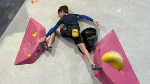 Dimi Hutchinson A view of Alex half way up a brightly coloured climbing wall