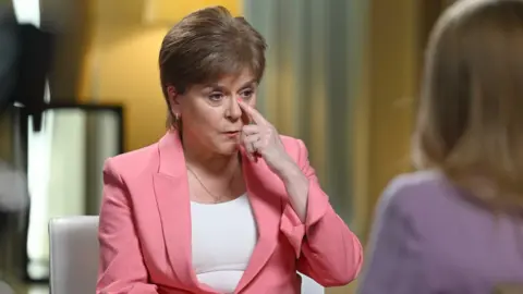 Sturgeon holds her finger up to the corner of her eye, appearing to wipe away a tear as she speaks to Laura Kuenssberg