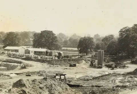 The Story/Durham County Council A building site, with the beginnings of a concrete tower, worker huts and trees in the background