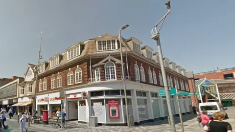 Google The Post Office in Grimsby. It is painted white and is a corner building. There is a cash machine to the front of the building.