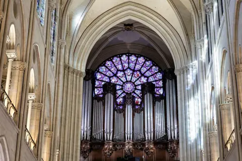 EPA An interior view of the cathedral shows ornate windows and rafters, with a purple stained glass window at the front above the many silver coloured pipes of the restored organ