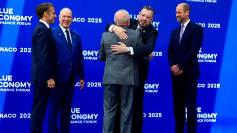 Reuters French President Emmanuel Macron, Prince Albert II of Monaco, Brazil's President Luiz Inacio Lula da Silva, Costa Rica's President Rodrigo Chaves Robles, and Prince William greet each other at the forum, standing in front of a blue wall with the Blue Economy logo written on it.