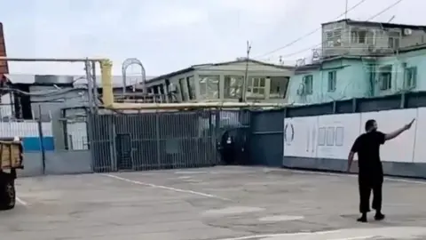 baza In this still from an unverified video posted on social media, a man is shown holding a knife, apparently in the courtyard of the IK-19 Surovikino facility