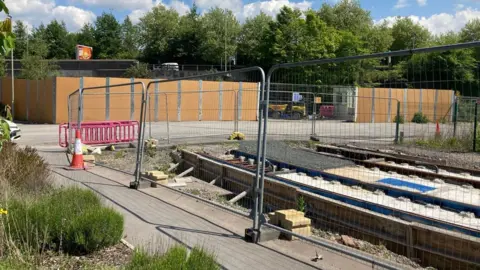 A tram line under construction, gated off by metal barriers.