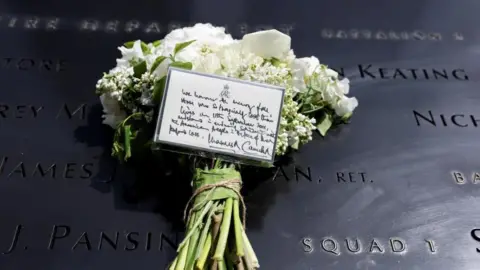 PA Media A bouquet of white flowers with a note from King Charles and Queen Camilla lies at the 9/11 Memorial 